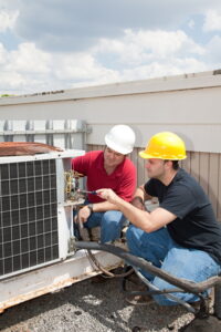 Two HVAC technicians working on a business rooftop.